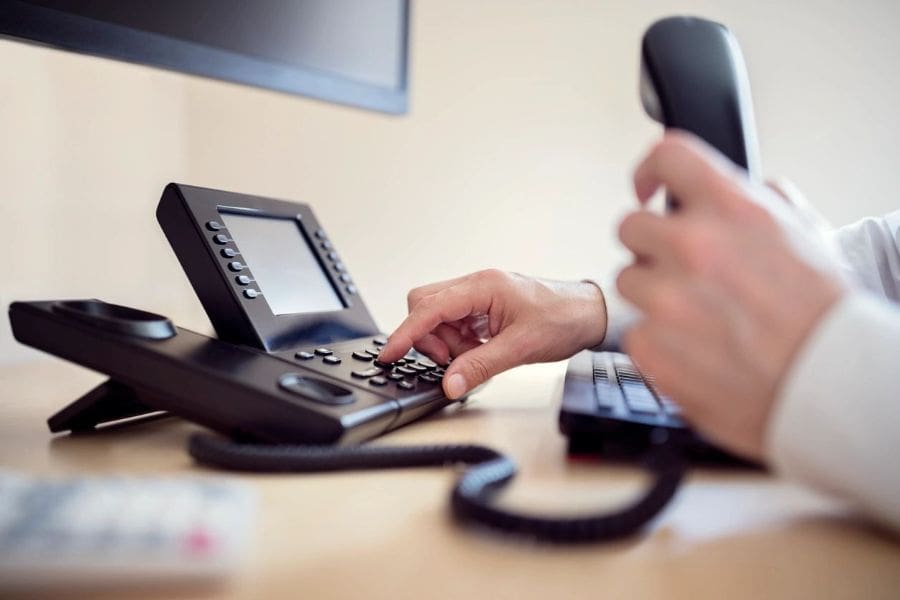 A person is using the phone on a desk.