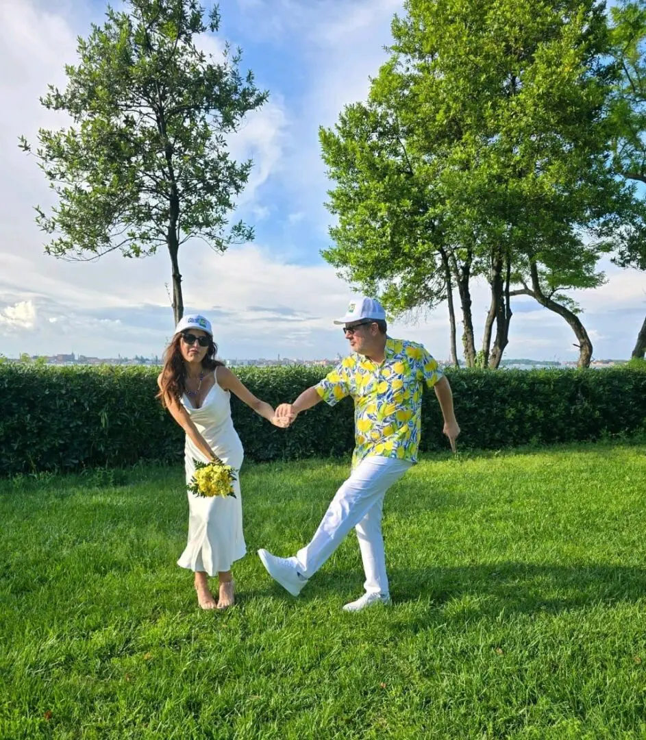 A man and woman holding hands in the grass.